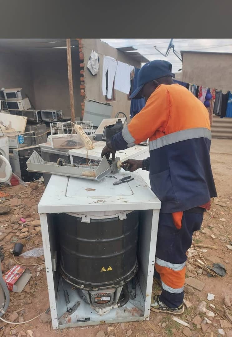 Technician in City Appliance Repairs uniform working on a top-loading washing machine