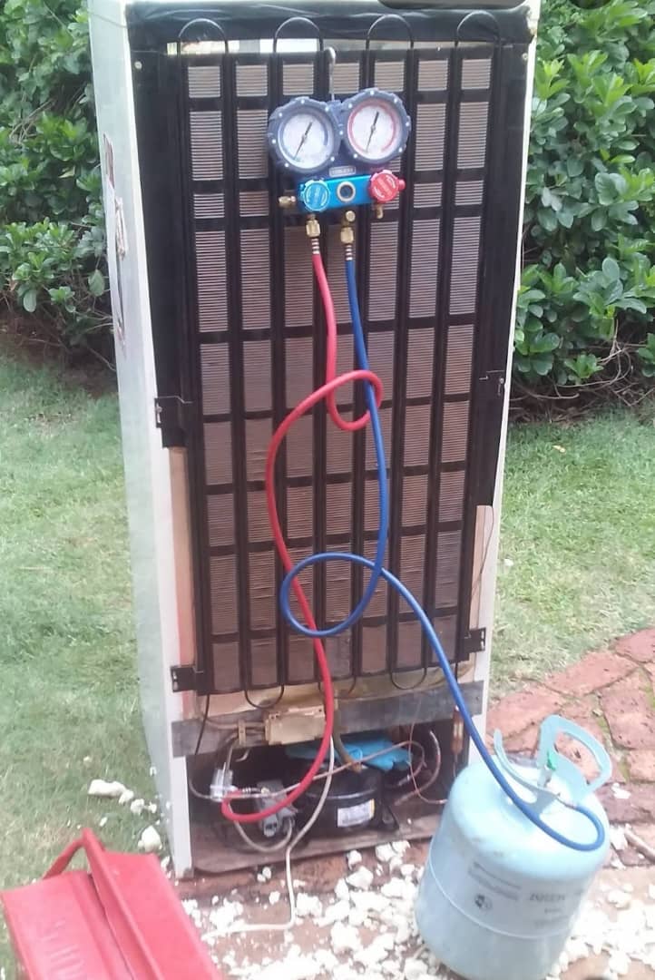 Fridge being regassed with pressure gauges and a refrigerant cylinder connected